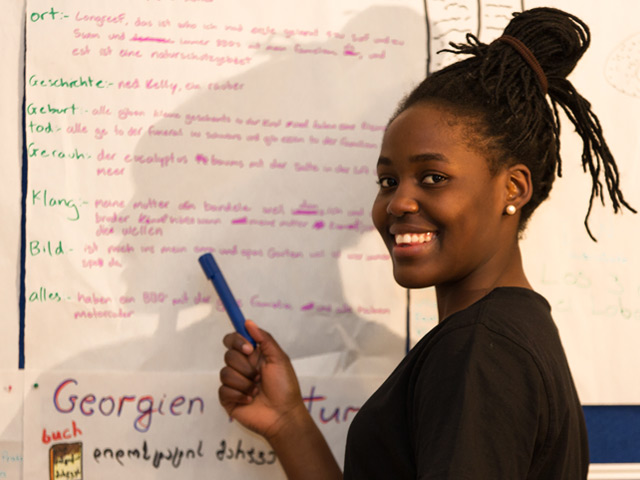 Junge Afrikanerin arbeitet lächelnd an FlipChart